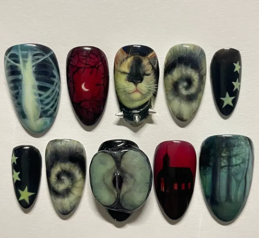 Dark gothic nails featuring eerie cat art, ribcage, forest silhouettes, stars, and surreal spirals for a mysterious, moody, and hauntingly artistic aesthetic