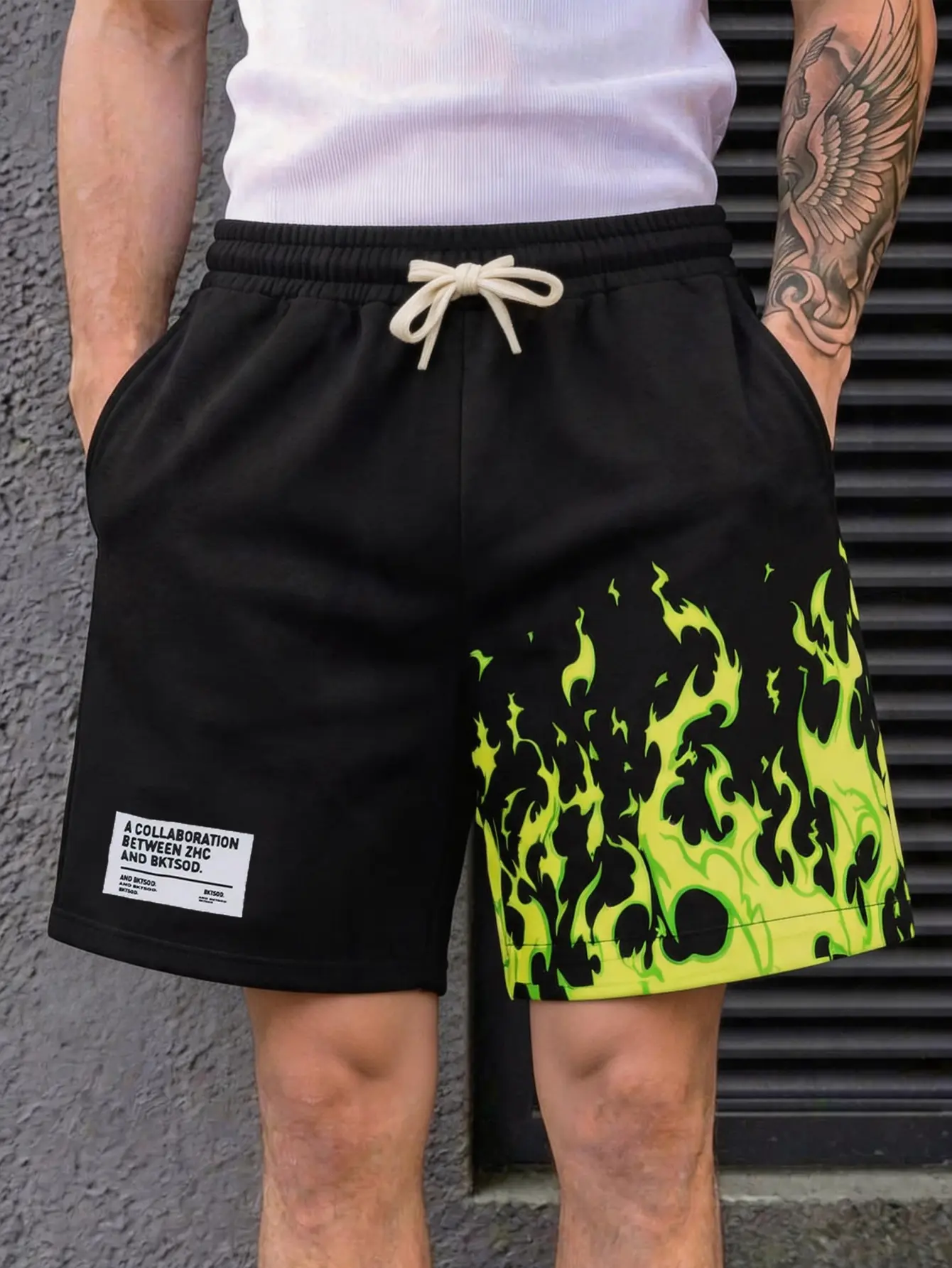 Men’s asymmetric flame print athletic shorts featuring an adjustable cotton drawstring elastic waistband and a loose, wide-leg fit. One-side large-area fluorescent flame pattern + fabric tag design. Breathable knit fabric with side pockets for storage. Hi