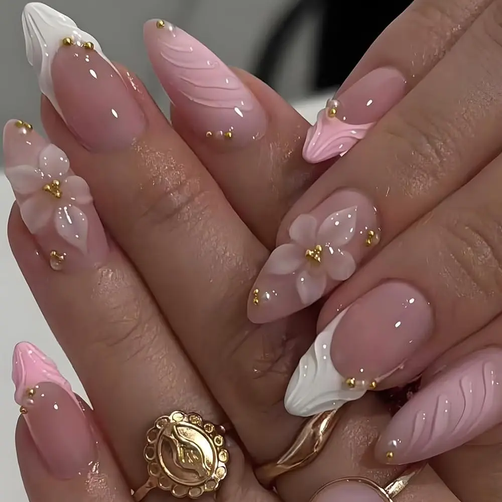 Pink French-style press-on nails featuring 3D sculpted floral designs and gold beads; almond-shaped tips.