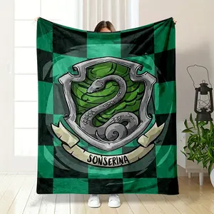This Harry Potter Slytherin themed blanket features a classic green and black checkered background with the college's iconic serpent badge, marked with the Spanish translation Sonserina below. It is