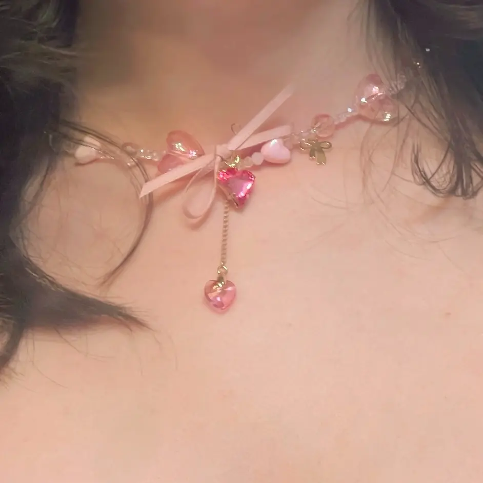 soft pink ribbon dangle necklace featuring delicate heart charms and a coquette-inspired design. lightweight, feminine, and perfect for everyday wear.