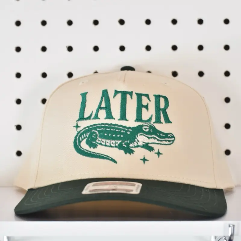 Later Gator Trucker Hat with Green Alligator Design and "LATER" Text on Beige Background