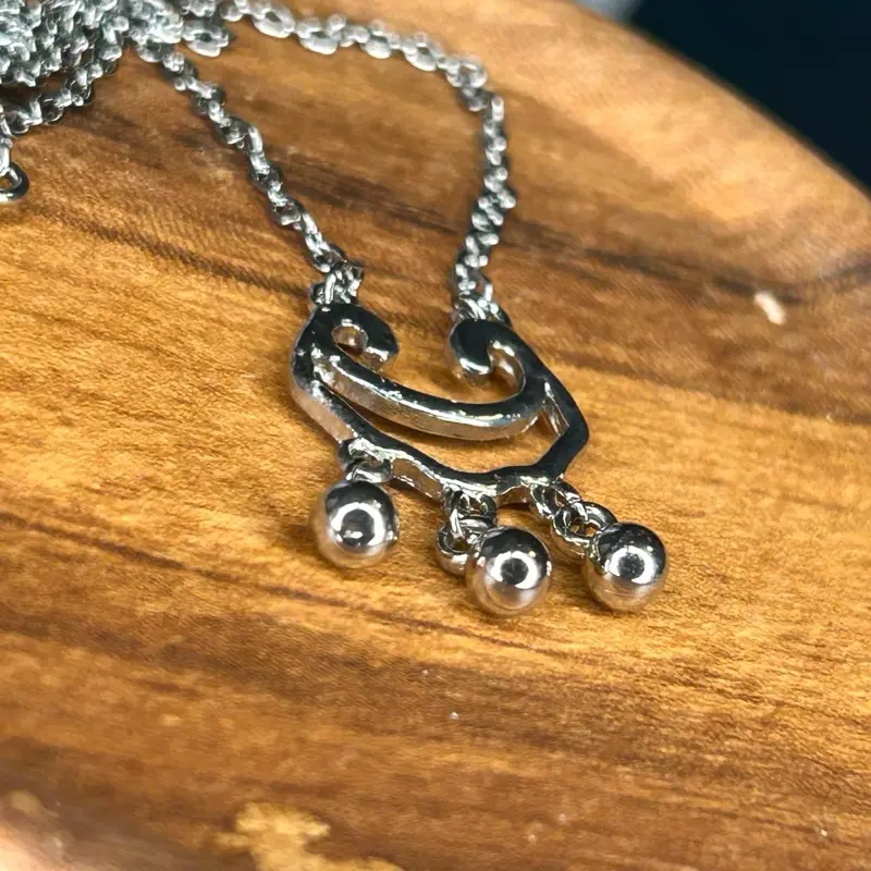 Silver-Toned Necklace with Unique Curved Pendant and Three Small Bells for Protection.