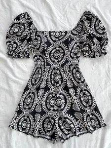 A women's black romper with white vintage ethnic-style patterns, square neckline, puff sleeves, cinched waist, Fitted, retro and sweet style, suitable for everyday outings, coffee shop visits, and casual summer occasions