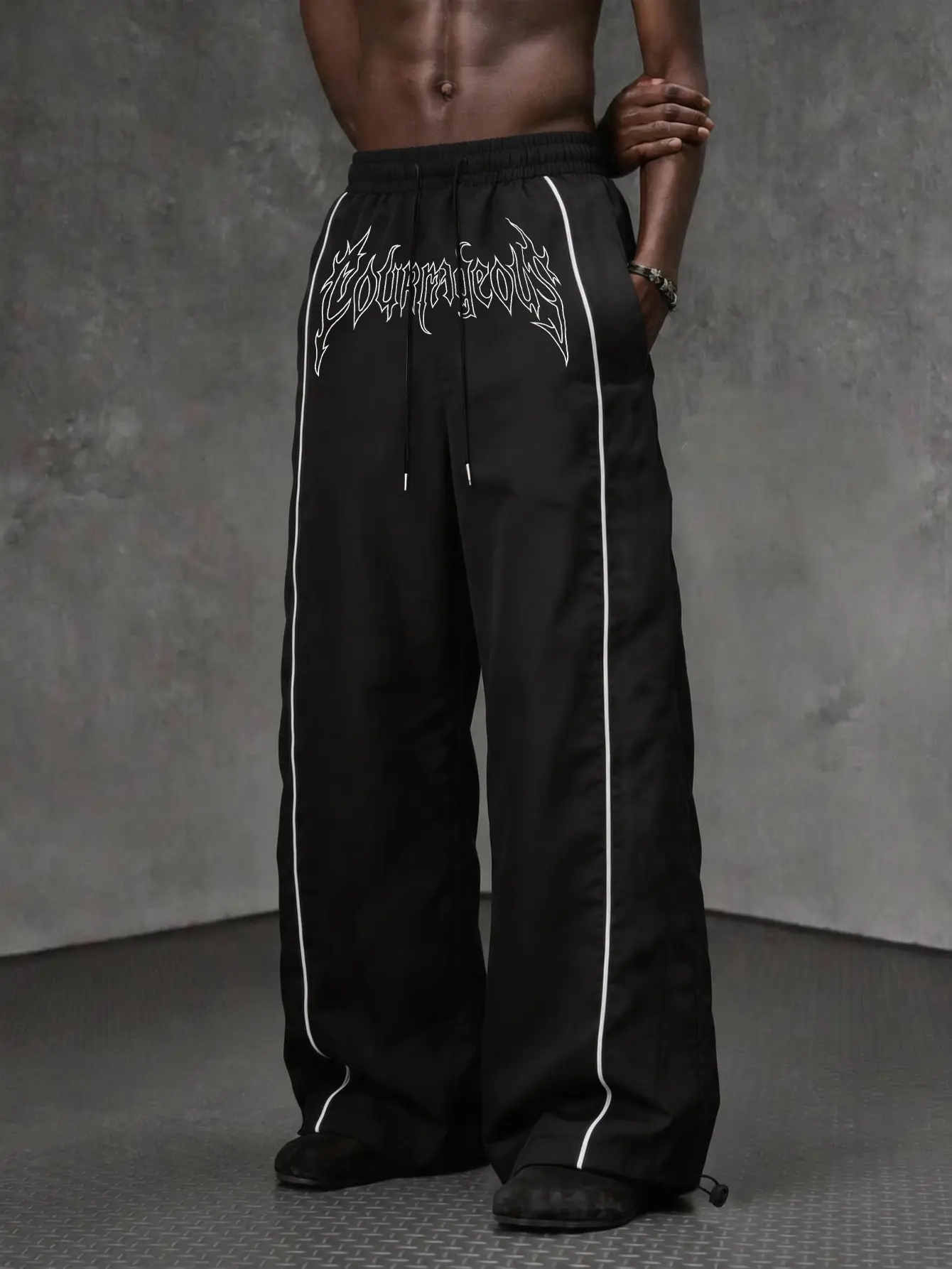 High-street dark aesthetic men’s loose casual pants featuring a gothic handwritten letter pattern, side contrast color line panels, an elastic waistband with drawstring, tapered cuffs, two-way wear design, hip-hop street skate style, relaxed drape, floor-