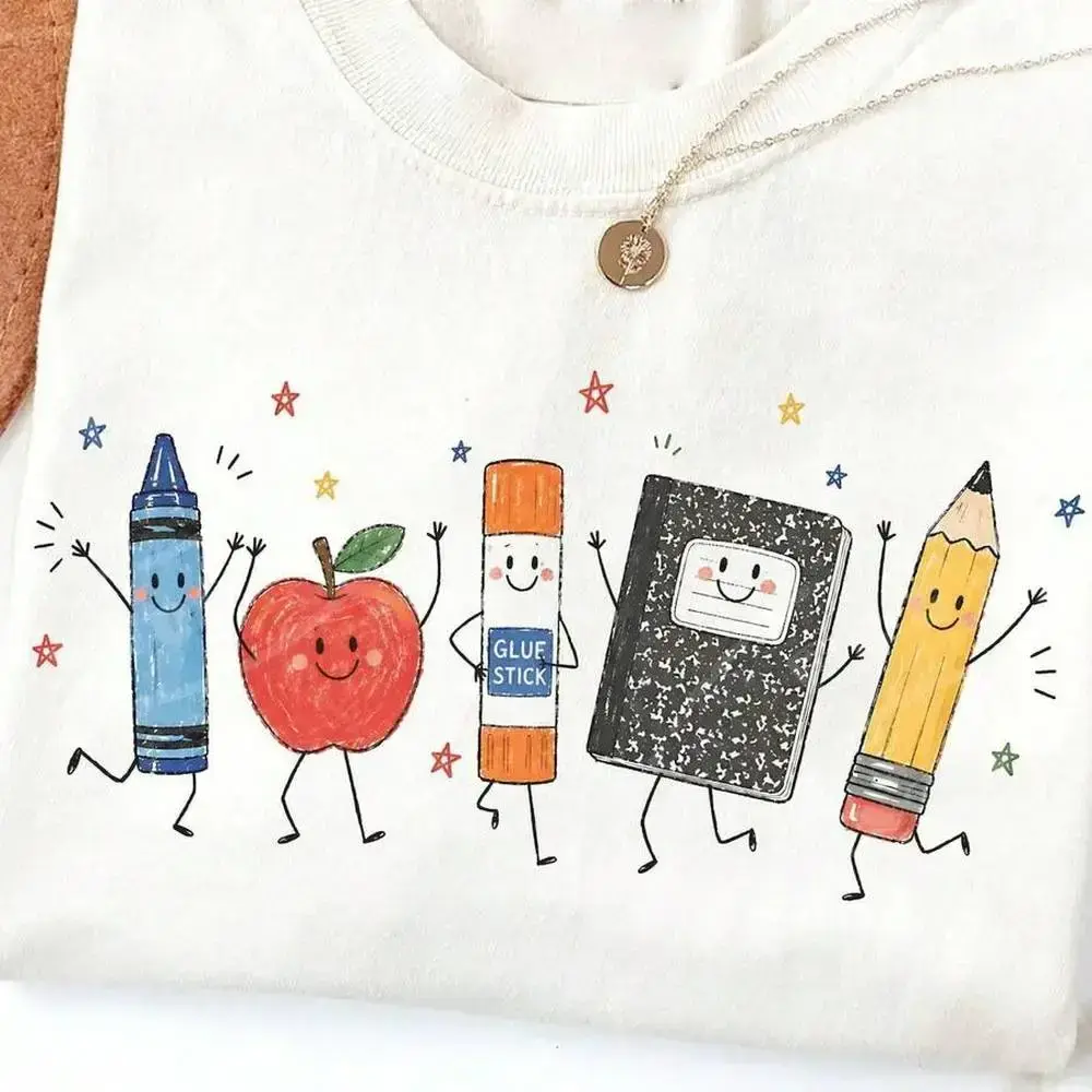 Cute cartoon school supplies graphic tee — preppy teacher/student T-shirt, kindergarten back-to-school top featuring smiling apple, crayon, pencil graphics