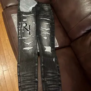 Amiri Distressed Denim Jeans with Logo Embroidery and Ripped Details for Men