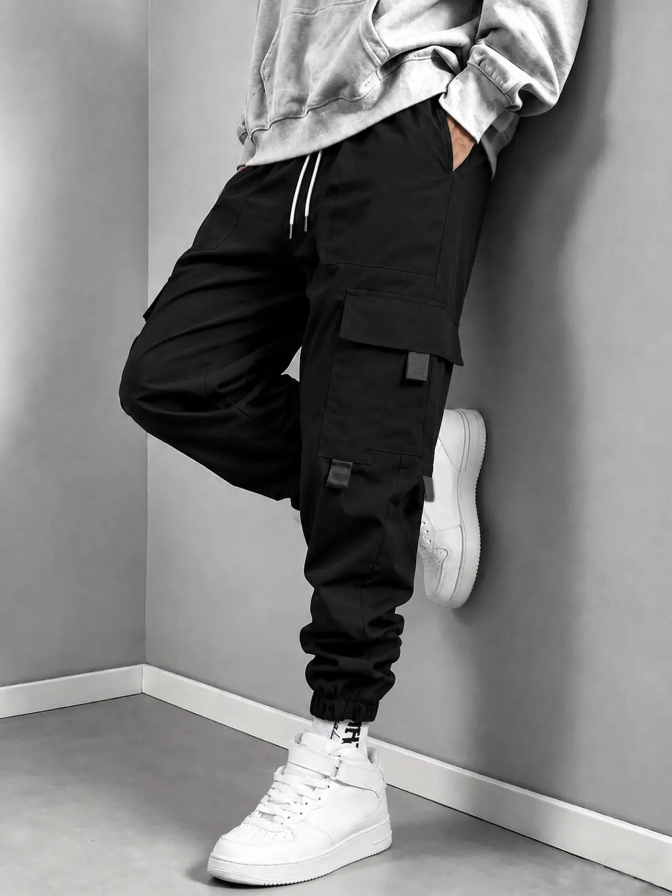 Men’s black jogger cargo pants made from woven fabric, featuring a loose jogger fit, double white drawstring waist, and elastic cuffs; suitable for street commuting and outdoor camping, ideal for American functional styling.
