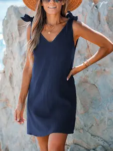 A women's navy blue V-neck sleeveless short dress with shoulder straps and bow decoration, suitable for seaside strolls, Beach, summer outdoor picnics. Comfortably loose and exudes vacation and leisure