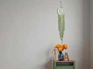 Handwoven boho macrame wall hanging, featuring a crocheted crescent moon and star dream catcher with long tassels. Crafted from green cotton with handmade bohemian styling, ideal for decorating nurseries, bedrooms and dorm spaces.