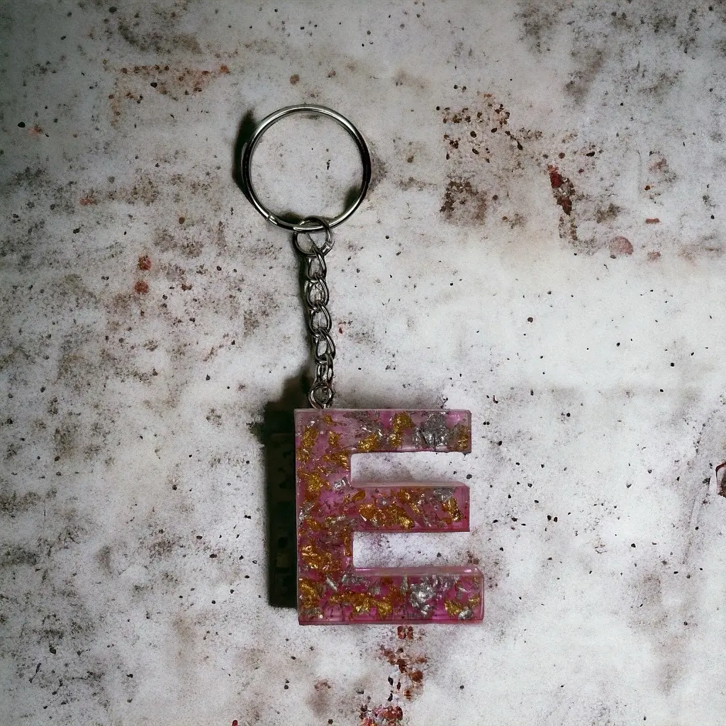 E Resin alphabet keychain pink with gold and silver flakes.
