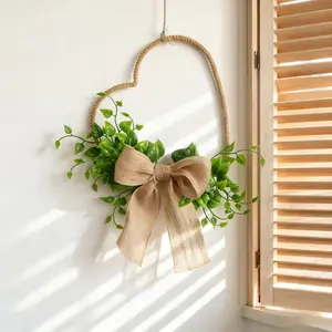 Heart-shaped wreath decorated with artificial green plants and bows. Ideal for decorating living rooms, bedrooms and window sills, a lovely piece to spruce up home ambiance.