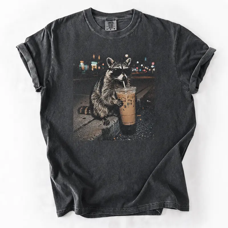 Three Raccoons Drinking Iced Coffee Comfort Colors T-Shirt with a funny Gen Z dank meme vibe, trendy cotton streetwear top and playful graphic gift for men and women alike.
