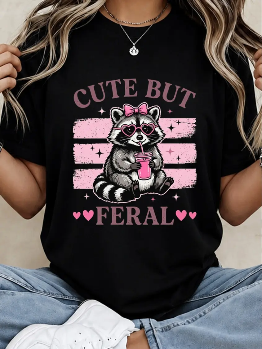Sarcastic Humor Cute But Feral Women Cotton Crew Neck T-Shirt Pink Heart Glasses Raccoon Graphic For Casual Loungewear And Everyday Wear