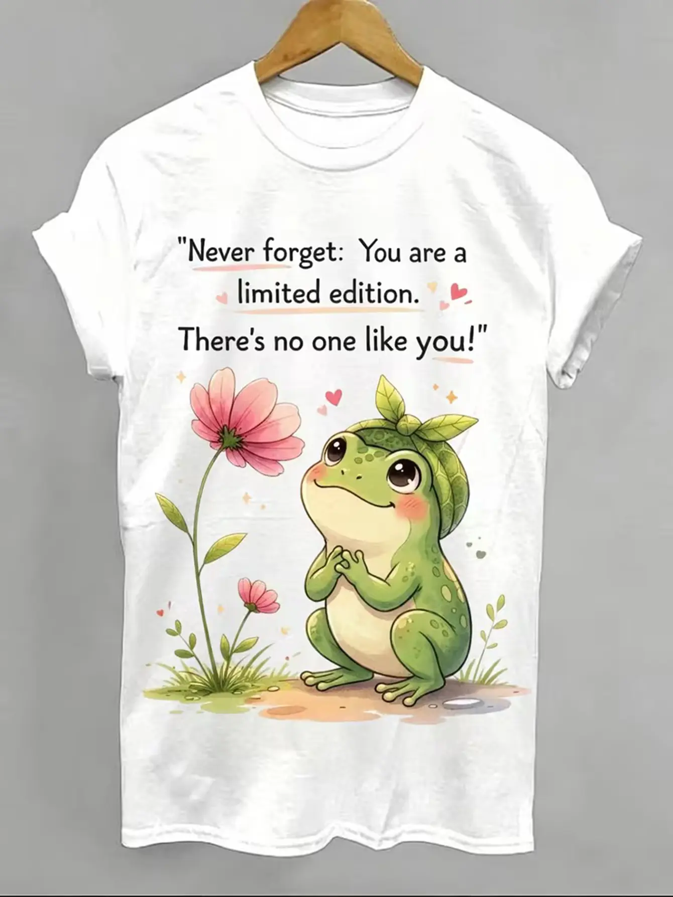This limited-edition women's adorable frog and floral print  T-Shirt  of the day  features a green frog paired with pink flower prints. The short-sleeved crew neck top displays an inspirational quote on the front, oversized tshirt women