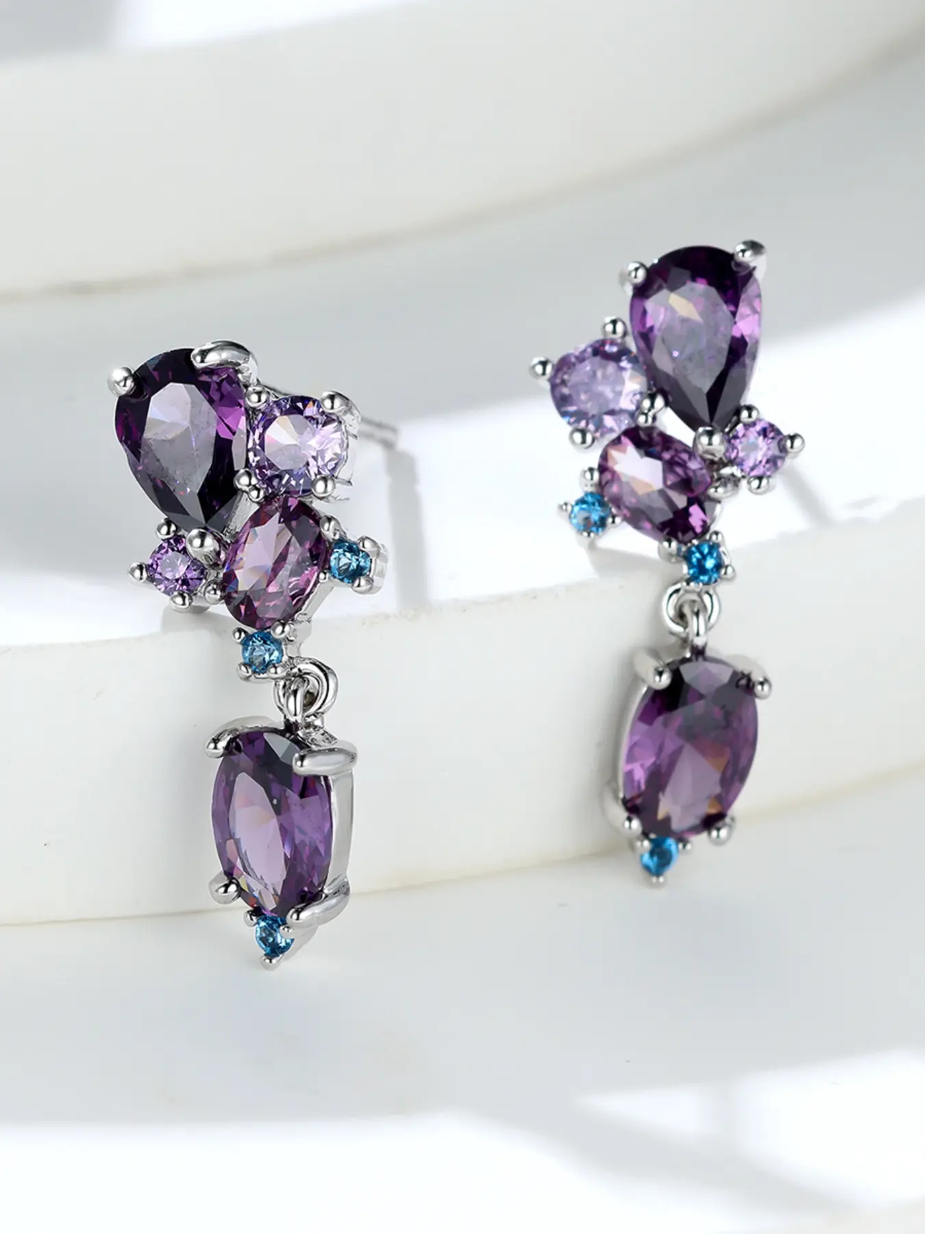 A pair of floral-shaped, purple synthetic crystal dangle earrings - stylish and high-end - suitable for women to wear as everyday earrings for special occasions like weddings.