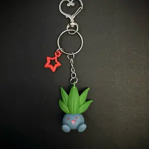 Oddish Character Keychain with Clip - Cute Green Plant Design & Red Star Charm for Fans