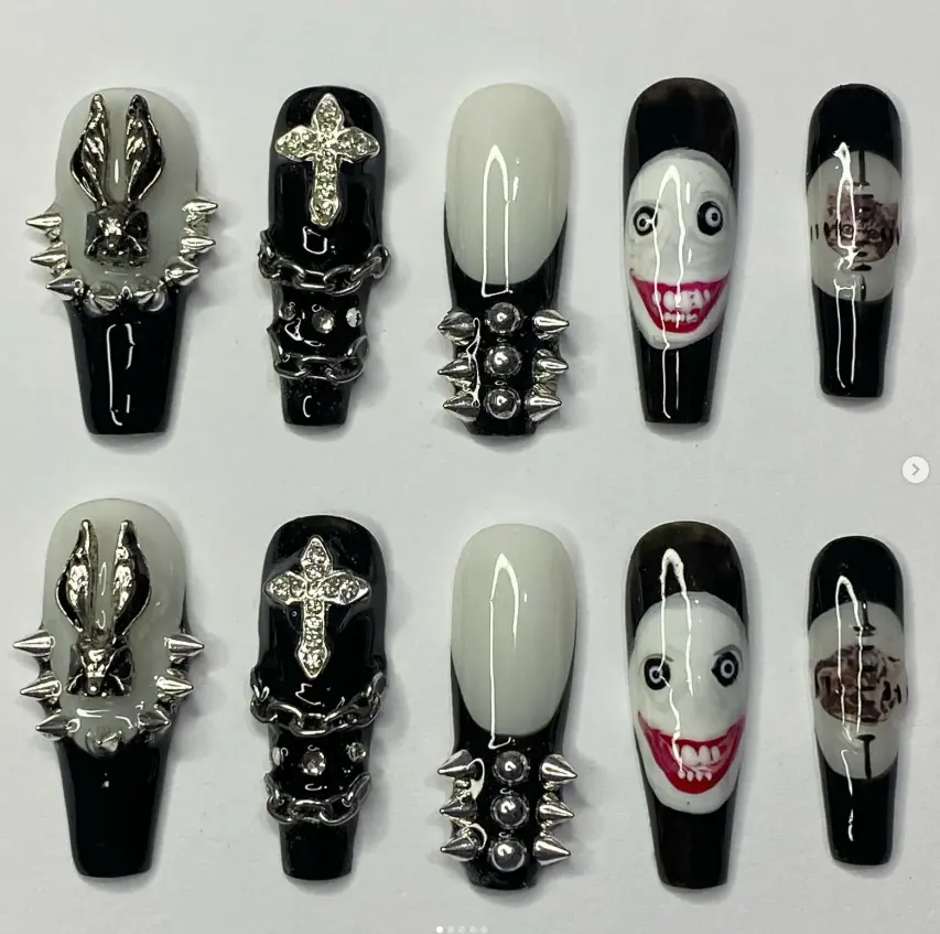 Edgy gothic nail set with creepy clown faces, spikes, chains, and silver cross accents in black and white, perfect for bold Halloween horror looks.