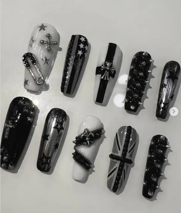 Edgy black and white punk nails with stars, crosses, spikes, chains, and Union Jack accents—perfect for a rebellious rock-inspired statement look