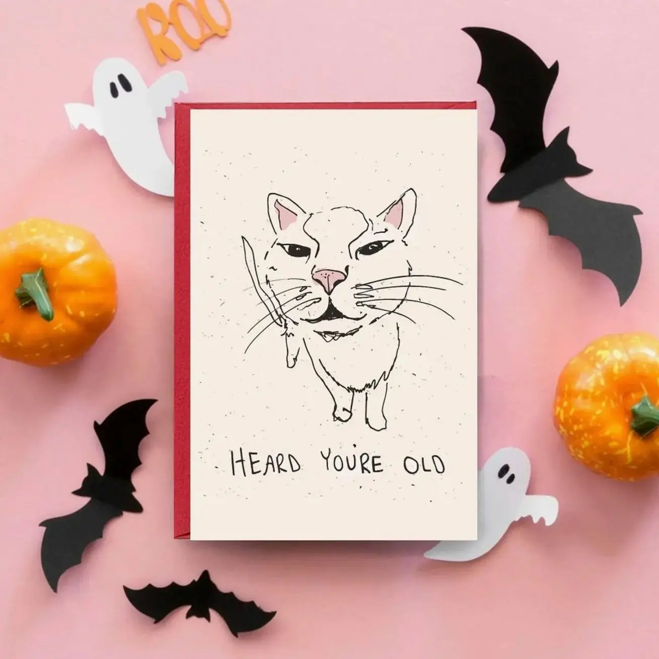 Savage Cat Birthday Roast Card - Smirking White Feline with Bloody Dagger & 'HEARD YOU'RE OLD' Sassy Greeting, Pink Ears & Nose on Beige Speckled Background