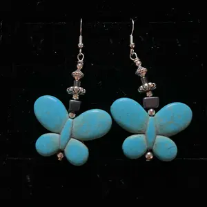 Navajo handmade sterling silver earrings adorned with a magnesite turquoise butterfly bead, hematite, silver daisy-shaped bead and silver hogan bead.