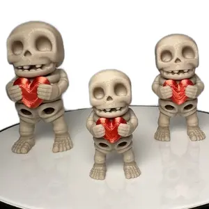 “Tiny Calaca” flexi figurine holding a red heart. 3D printed skeleton that sinks its head and torso into itself when standing and fully articulates when lifted. Keychain option available also! Bone color body and silky red heart Decor Gift