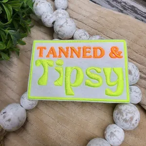 Tanned and Tipsy embroidered on felt iron-on patch.