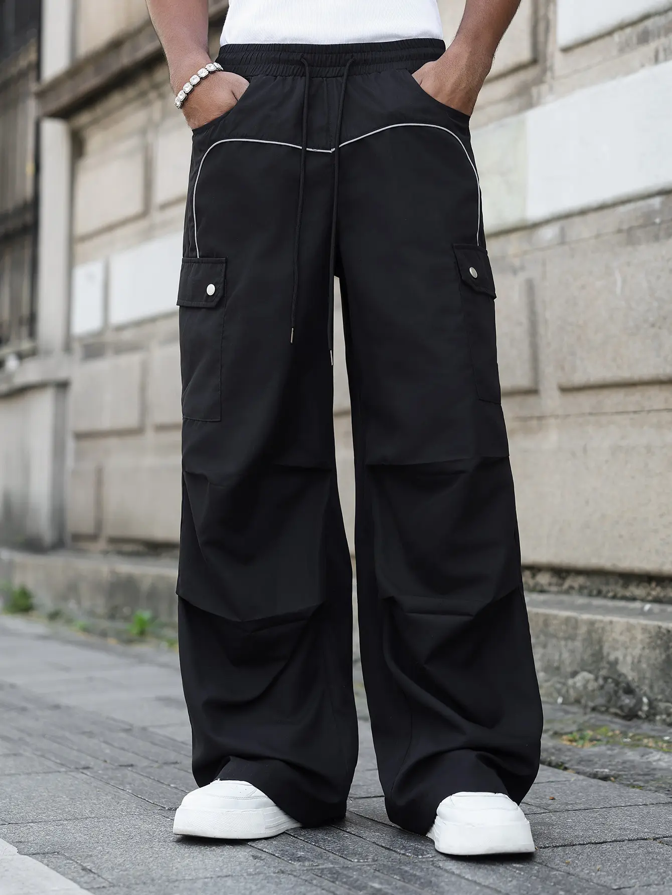 Men’s black wide-leg cargo pants featuring a loose fit and white striped patchwork design, equipped with large-capacity functional pockets; suitable for street fashion looks, campus everyday wear, and daily commuting outfits.