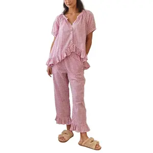 Women’s gingham plaid two-piece pajama set: button-front short-sleeve babydoll shirt with an irregular ruffle hem, paired with matching gingham pants. PJ lounge sleepwear loungewear.