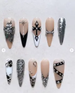 Bold gothic nail design with nude, black, and silver tones featuring crosses, 3D metallic flowers, chrome textures, studs, and gemstone accents