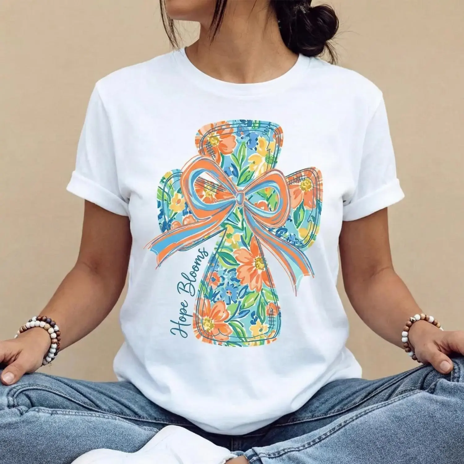 Cotton casual round-neck short-sleeve summer T-shirt with vibrant cross and bow design “He Is Risen” printed graphic tee machine washable not dry cleanable made in USA Popular viral Christian Easter trend tee