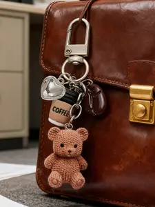 A coffee teddy bear keychain bag charm, a cute and stylish accessory for your bag and keys! This charm includes a knitted teddy bear, a mini coffee cup, a coffee bean, and a sparkling heart pendant.