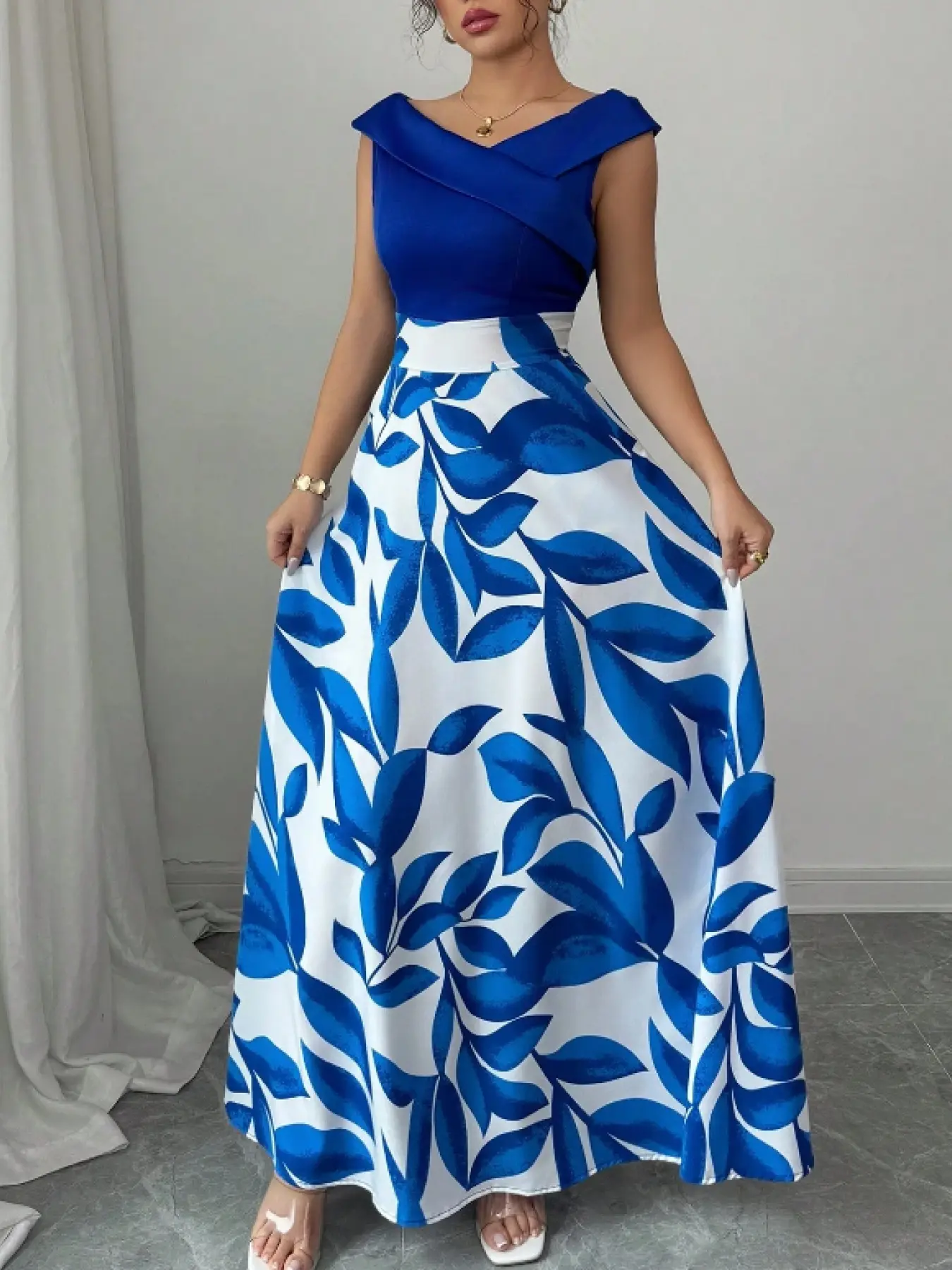 A sleeveless navy blue dress with blue and white leaf print panels and a V-neckline with a flared long skirt, Casual chic outfit, suitable for dinners, upscale dates, art exhibitions
