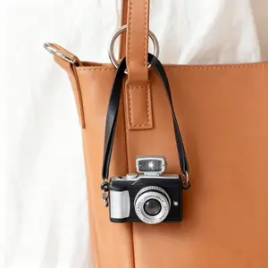 A Small Realistic Camera Featuring A Strap Ornament, Suitable For Use As A Keychain Or A Charm For Bags.
