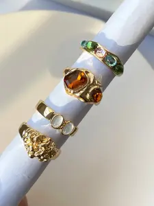 A set of four vintage gold-colored rhinestone rings in a colorful design, perfect jewelry for women