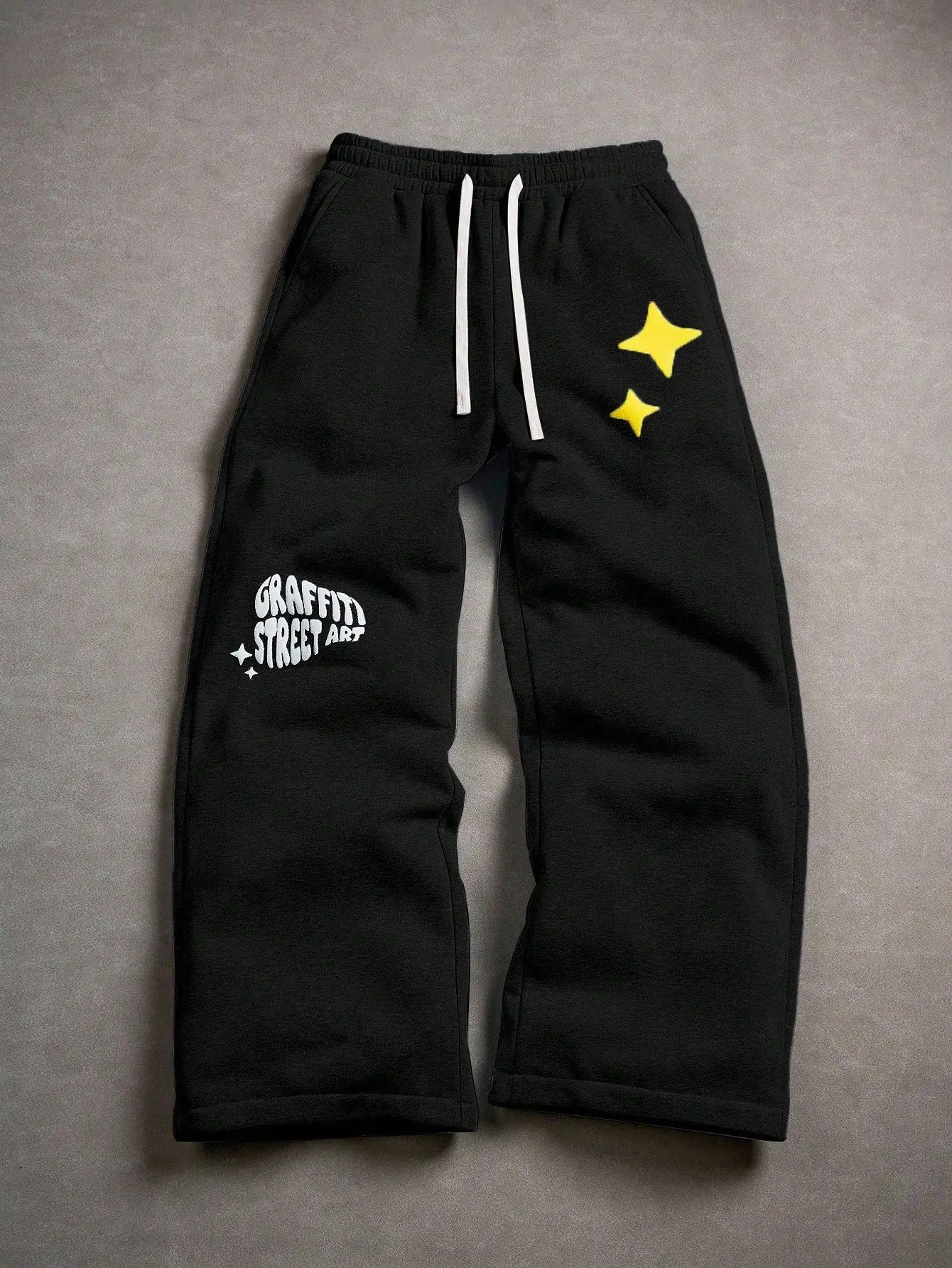 One piece men’s black wide leg casual sweatpants featuring color block drawstring design and star graffiti print; urban relaxed style with a solid black main color that is stable yet versatile. High waisted color block drawstring waistband paired with sta