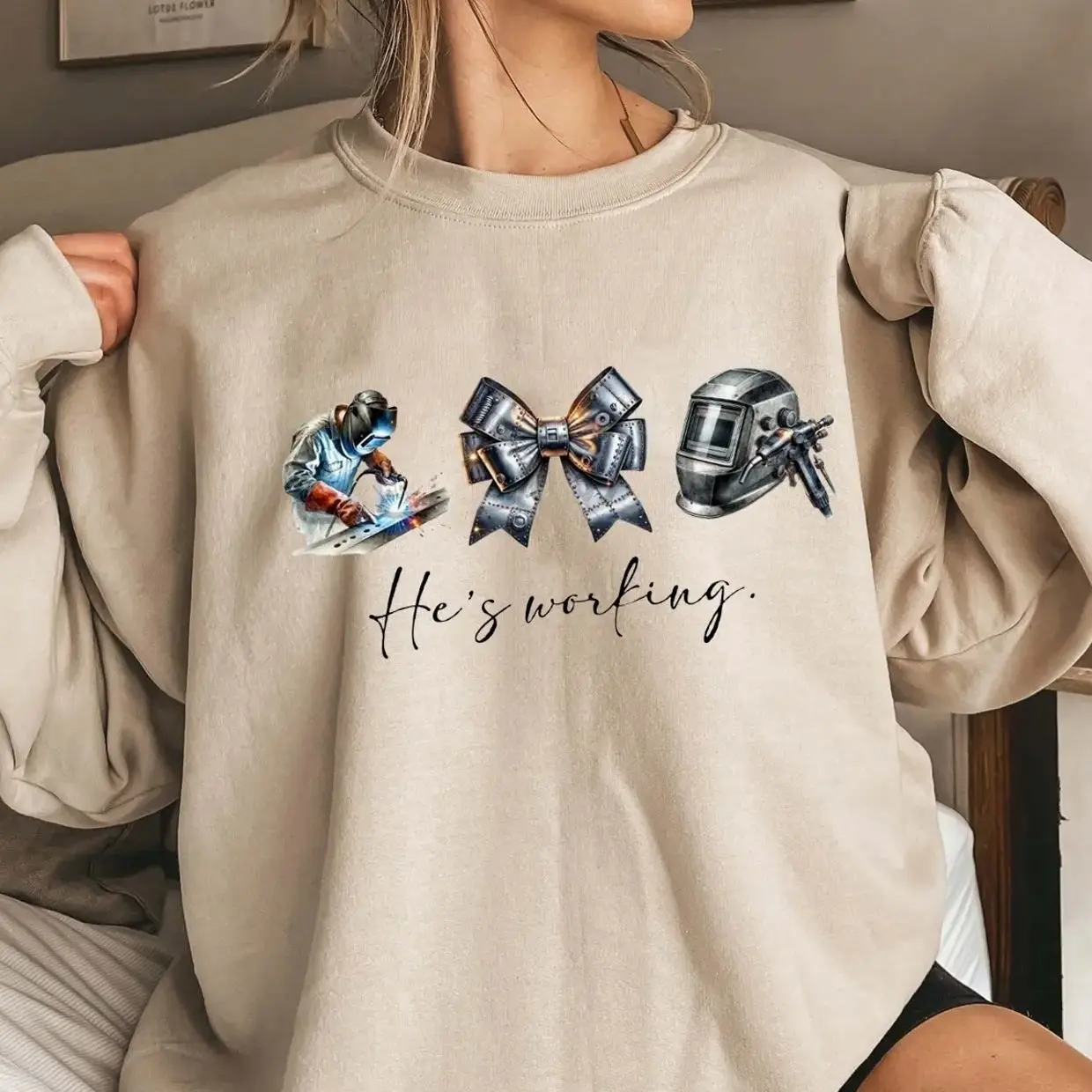 He’s Working Welder Sweatshirt – Blue Collar Wife Girlfriend Shirt, Welding Helmet Bow Graphic, Welder Wife Gift, Tradesman Family Pride Crewneck Sweatshirt