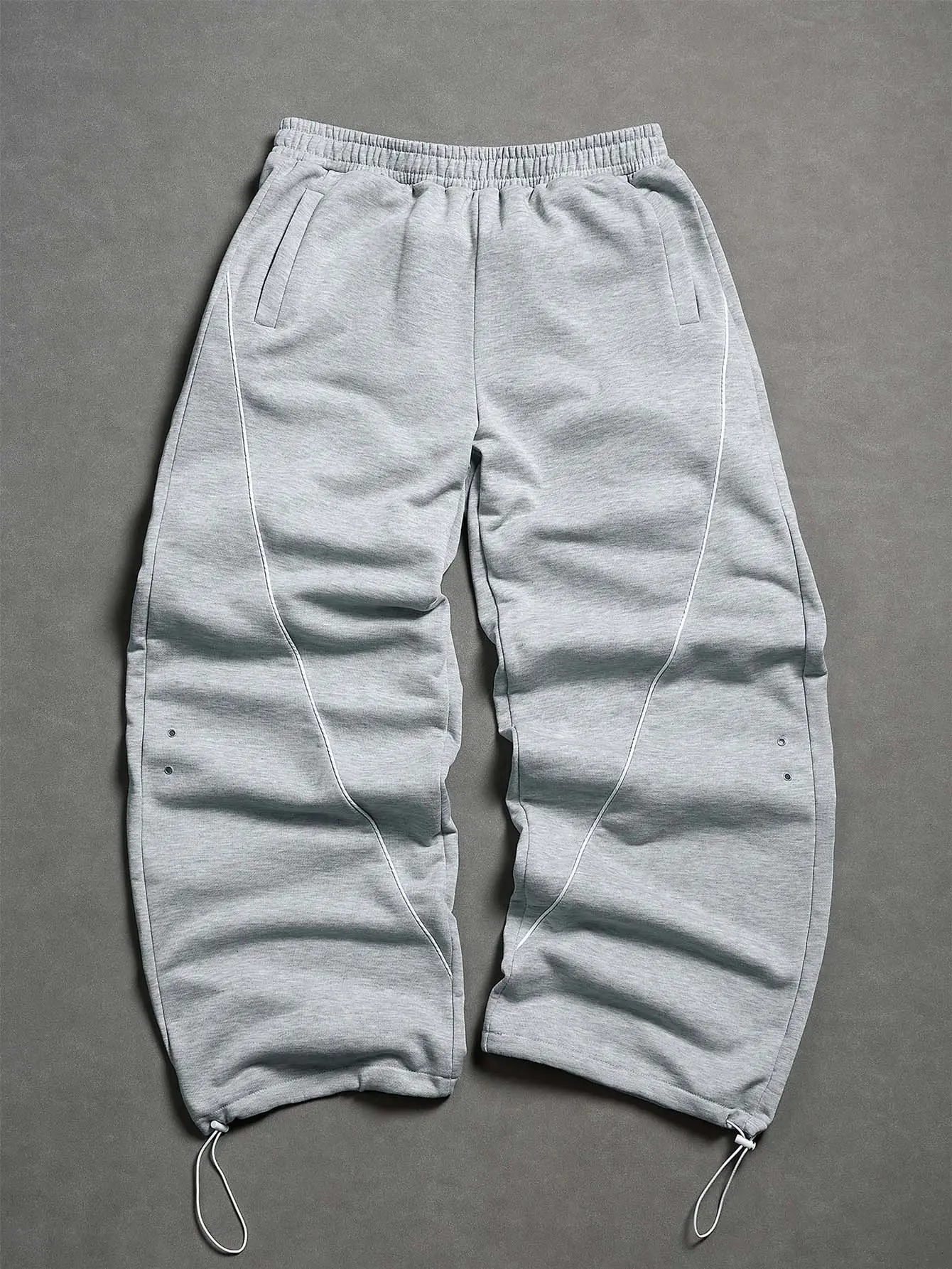 Unisex light gray sweatpants with curved topstitching, drawstring hem, wide legs — white contrast stitching, metal eyelets, elastic waistband, side pockets, heavyweight knit; high street tech casual pants for skating, gym, and commuting