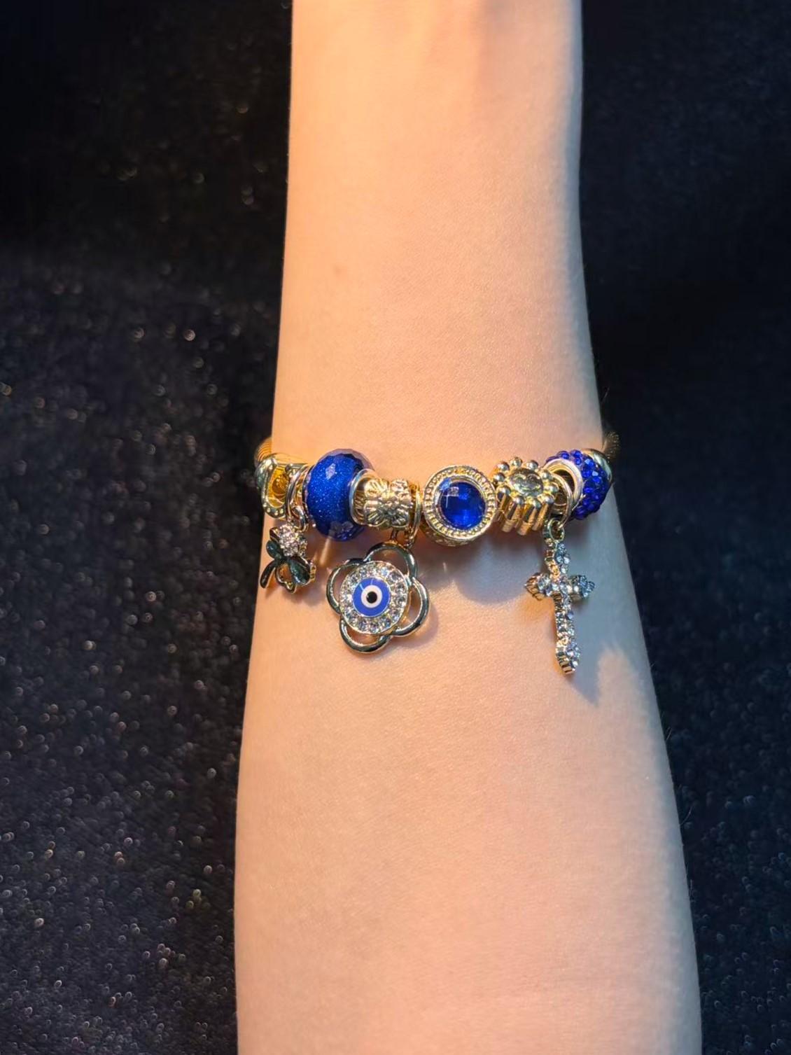 Women's Gold-Tone Open Cable Charm Bangle, Stackable Costume Jewelry Bracelet with Evil Eye, 4-Leaf Clover, Cross, Sparkling Blue Crystal Beads Charms