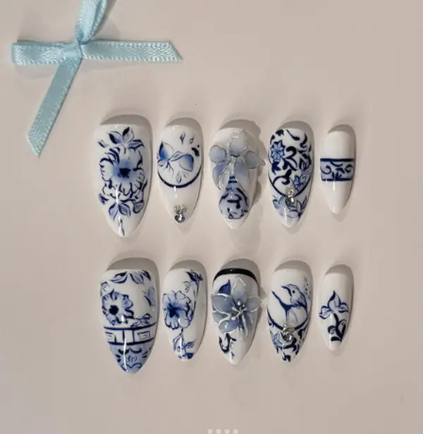 Blue Porcelain nails – elegant white base with intricate cobalt floral patterns, delicate 3D petals, and pearl accents inspired by classic Chinese porcelain artistry