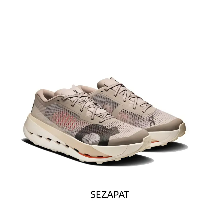 Sand Beige And Creamy White Technical Running Shoe Featuring A Dark Grey Anatomical Overlay, A Hollow-Core Segmented Midsole, And A Minimalist Orange Side Stitch Accent