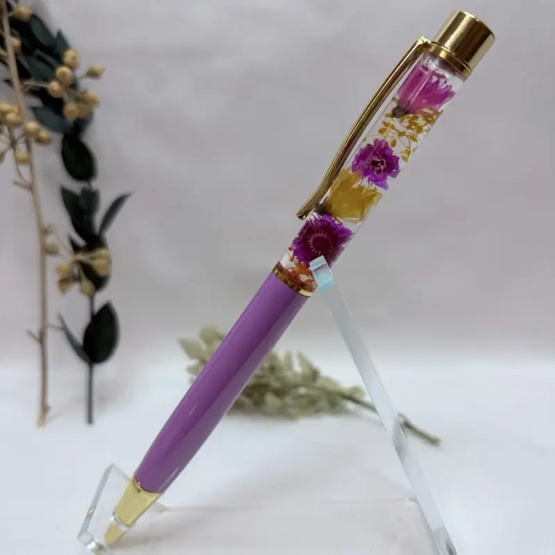 Amethyst Meadow-Handcrafted herbarium pen featuring real preserved pink and purple flowers suspended in crystal-clear oil. Refillable black ink with elegant gold accents. Includes a gift box and extra refill—perfect for journaling and flower lovers