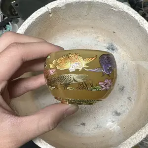 A masterpiece, this handcrafted Jianzhan teacup features a golden glaze, hand-painted goldfish, and a luminous finish.