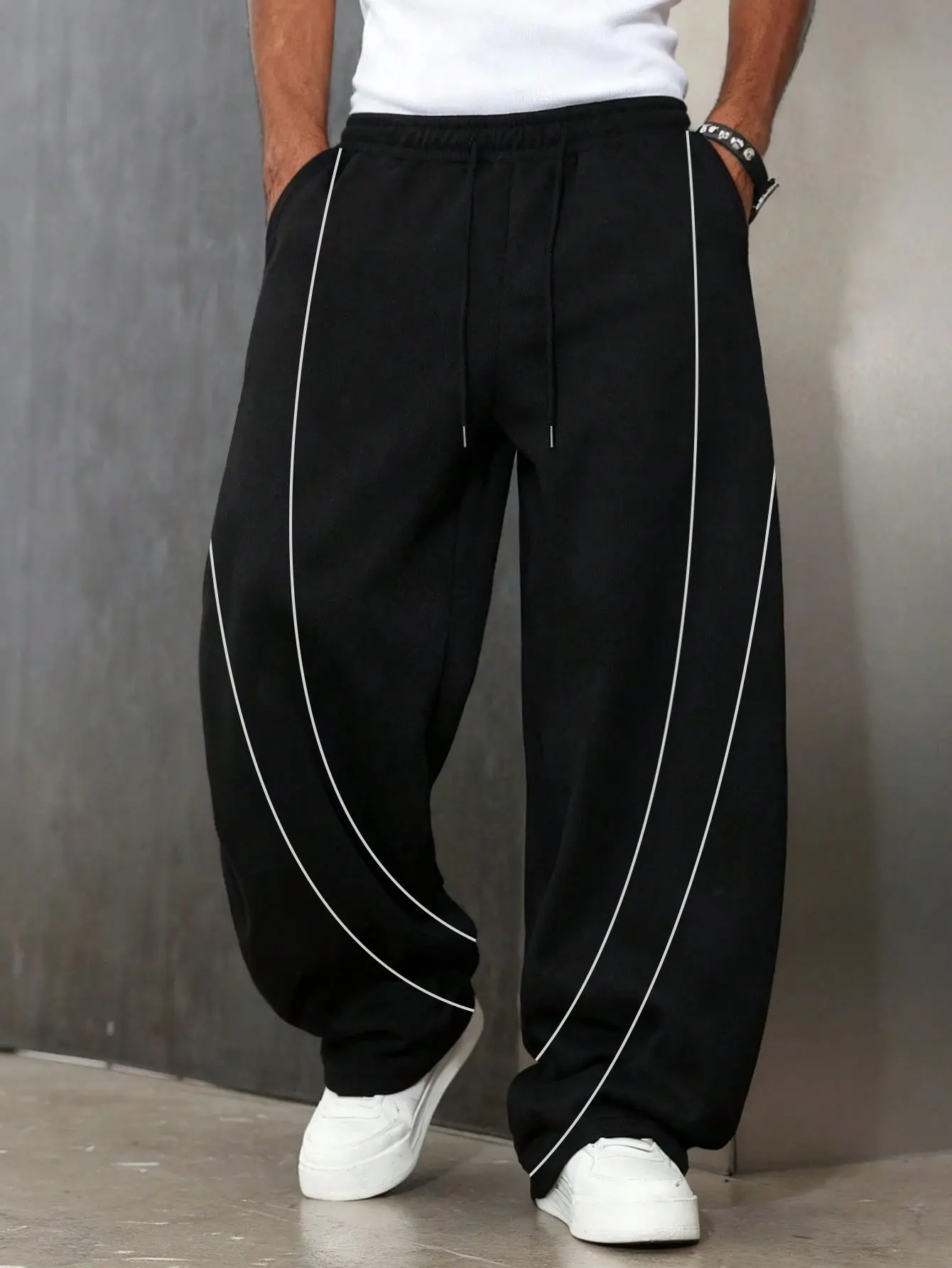 One black men’s jogger sweatpants featuring a wide leg and drawstring waist, street style minimalist design. Side double layered curved stitching with visible lines paired with an elastic drawstring waistband, symmetric flap pockets, suitable for men when