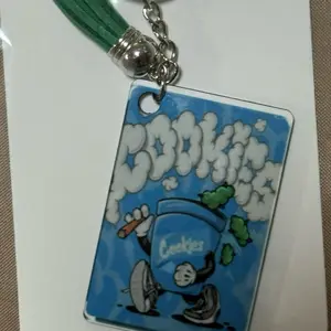 Cookies Brand Smoking Keychains with Green Tassel and Blue Design Featuring Character and Clouds