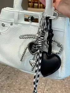 A niche, personalized, and refined ambiance pendant featuring bow and heart design elements, with braided lanyard decoration for easy portability. Versatile in use, suitable as a bag pendant or keychain, ideal for commuting and shopping