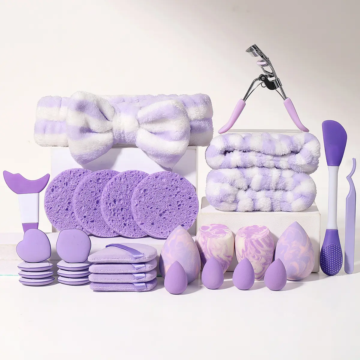 31 multifunctional makeup tools, 4 large and 4 small makeup balls, 8 finger powder puffs, 4 facial cleaning sponges, 4 triangular powder puffs, eyelash curlers, tweezers, dual head massagers, plush headbands, and hairline wristbands. Makeup tool set