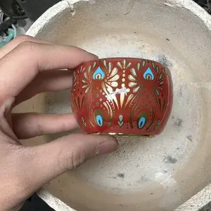 A masterpiece, this handcrafted Jianzhan teacup features a red glaze, hand-painted peacock eyes, and glows in the dark.